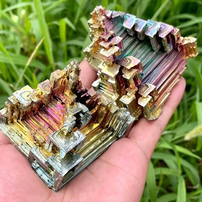 Iridescent Bismuth Metal Freeform Castles with unique stair-step formations and rainbow colors, held in a hand.