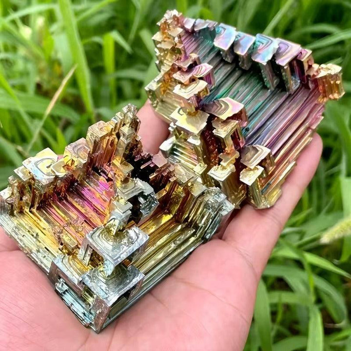 Iridescent Bismuth Metal Freeform Castles with unique stair-step formations and rainbow colors, held in a hand.