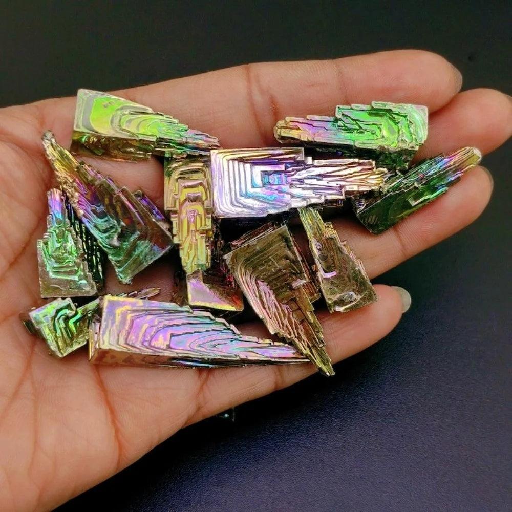 Hand holding iridescent Bismuth Crystal Pyramids for manifestation, creativity, and transformation.