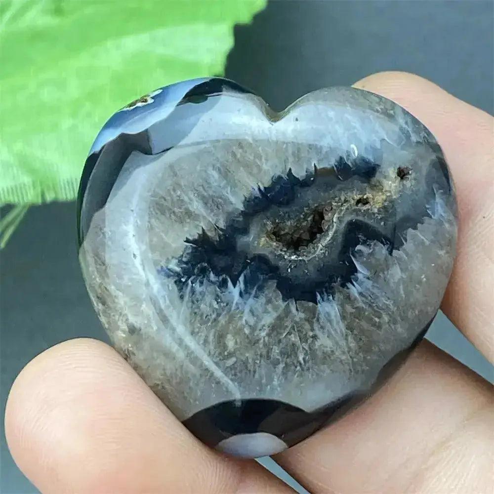 Polished Black Agate geode heart with a sparkling druzy crystal cave interior, held in a hand.