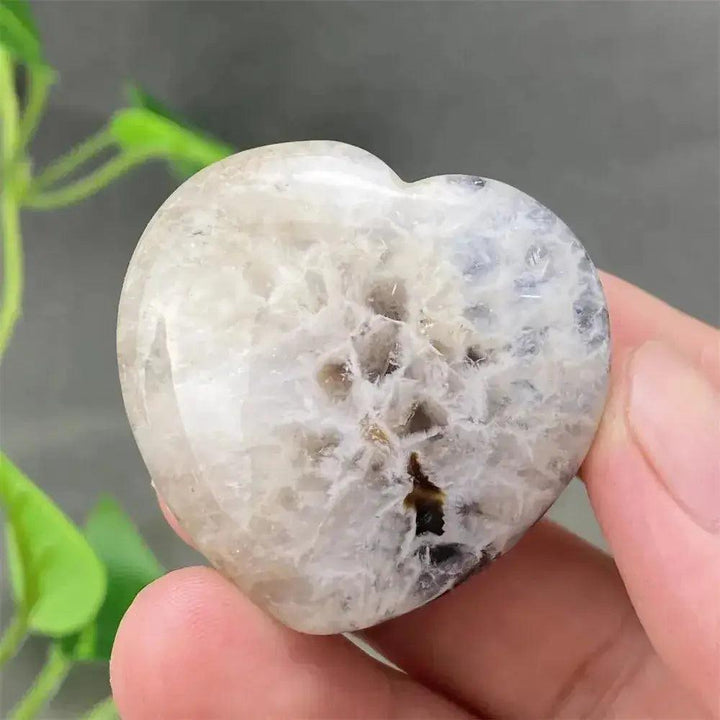 Polished Black Agate geode heart with a sparkling druzy crystal interior, held in a hand.