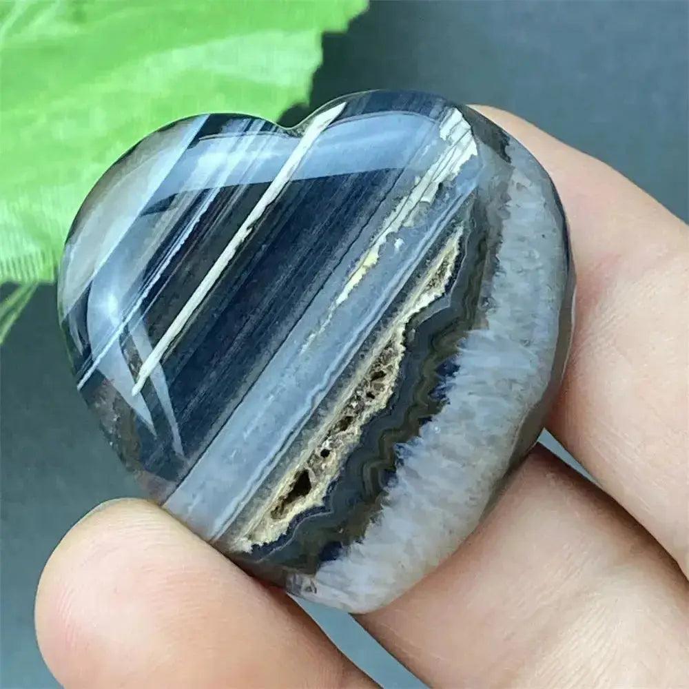 Polished black agate geode heart with natural gray bands, a druzy crystal cavity, and grounding energy.