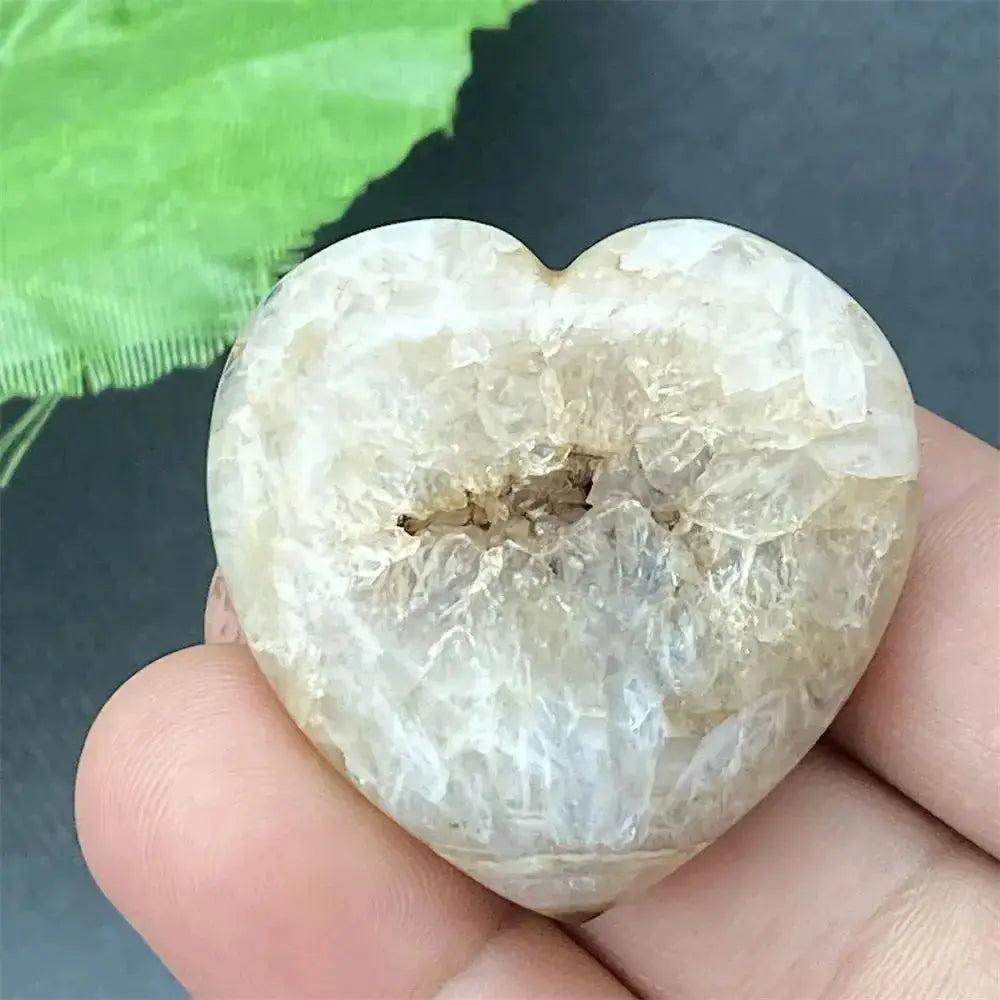 Polished Black Agate geode heart with a sparkling druzy crystal cave interior, held in a hand.