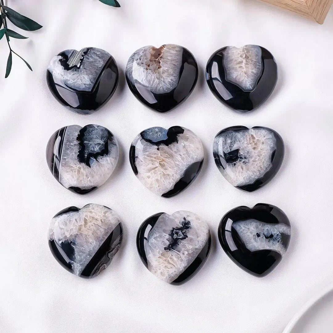 Nine polished black agate heart palm stones from Crystal Destiny, each with a unique white druzy crystal cave.