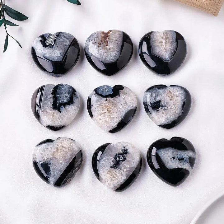 Nine polished black agate heart palm stones from Crystal Destiny, each with a unique white druzy crystal cave.