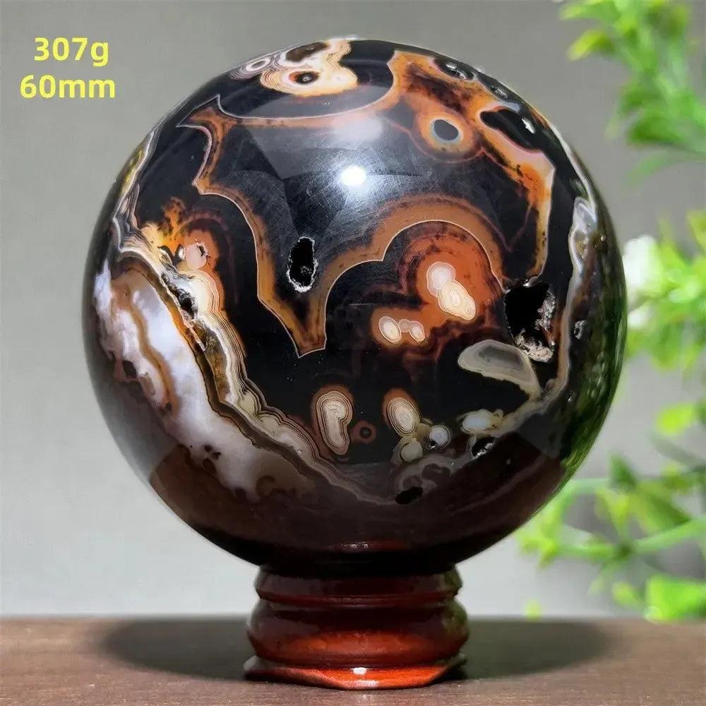 Polished Black Banded Agate Sphere with dramatic black, charcoal, and white striations on a wooden stand.