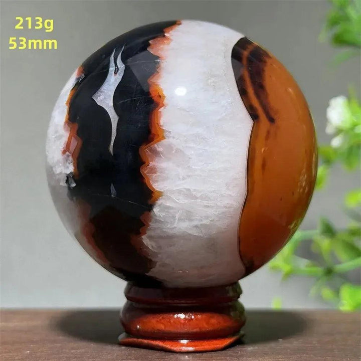Polished Black Banded Agate sphere with dramatic black, white, and orange striations on a wooden stand.