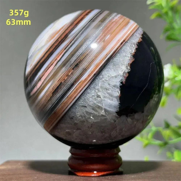 Polished Black Banded Agate Sphere with striking black, brown, and white striations, a raw druzy band, and wood stand.