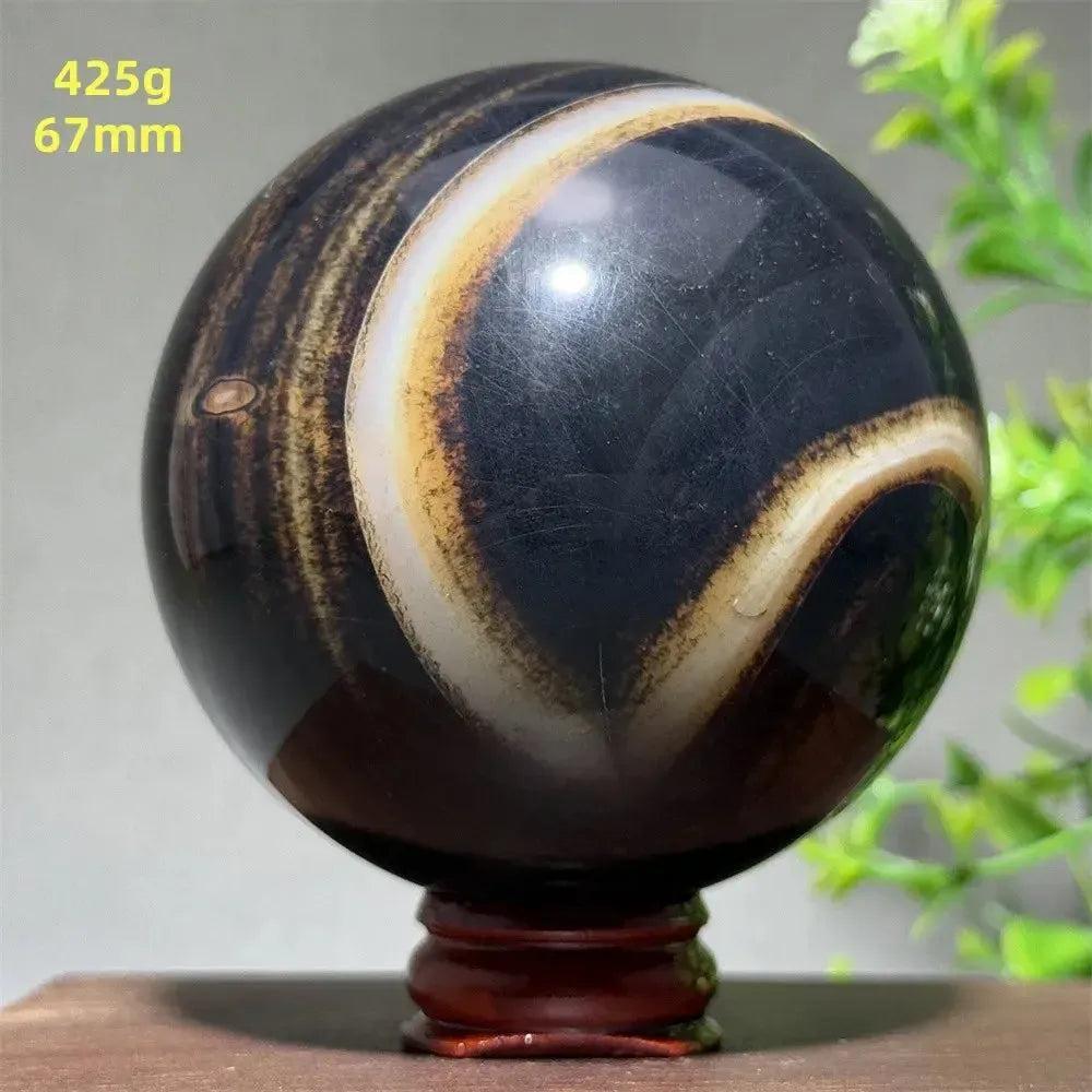 Black Banded Agate Sphere: Polished 67mm sphere with dramatic black, charcoal, and white striations on a wooden stand.