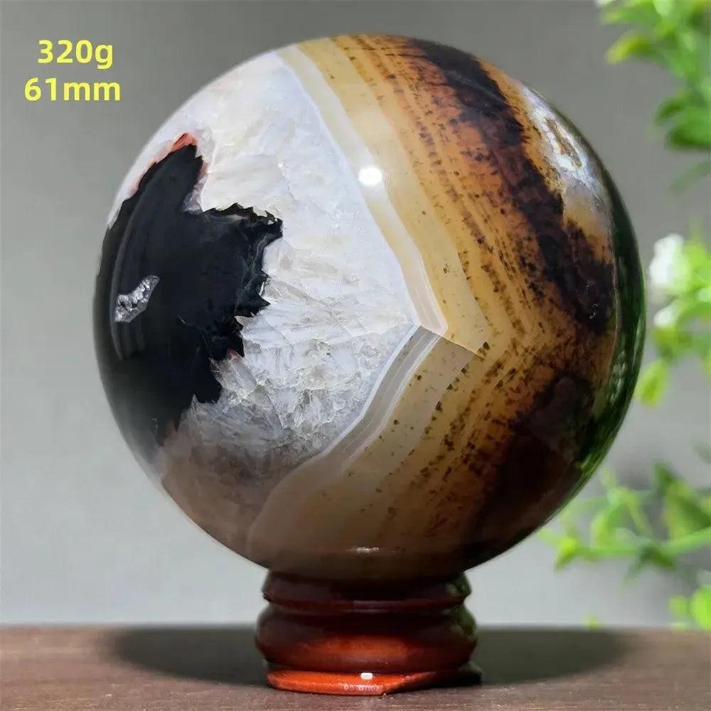 Polished Black Banded Agate Sphere with dramatic black, white, and brown striations on a wooden stand.