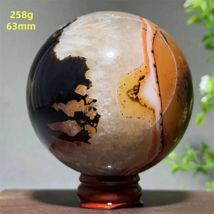Polished Black Banded Agate sphere with dramatic black, charcoal, and white striations on a wooden stand.