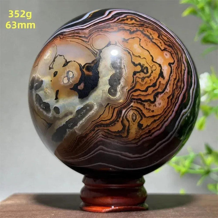 Polished Black Banded Agate Sphere, 63mm, with dramatic black, charcoal, and orange striations on a wooden stand.