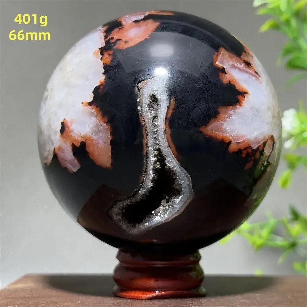 Black Banded Agate Sphere with Stand, showcasing dramatic black, white, and orange striations with a sparkling geode.