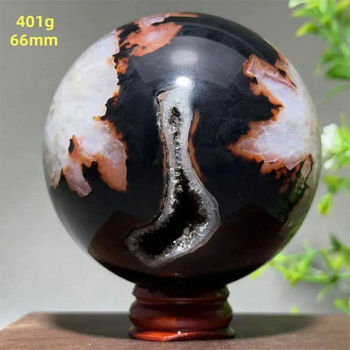 Black Banded Agate Sphere with Stand, showcasing dramatic black, white, and orange striations with a sparkling geode.