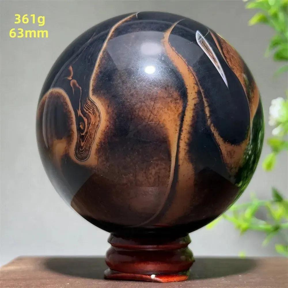 Black Banded Agate Sphere with dramatic black and brown striations, 63mm, on a wooden stand.