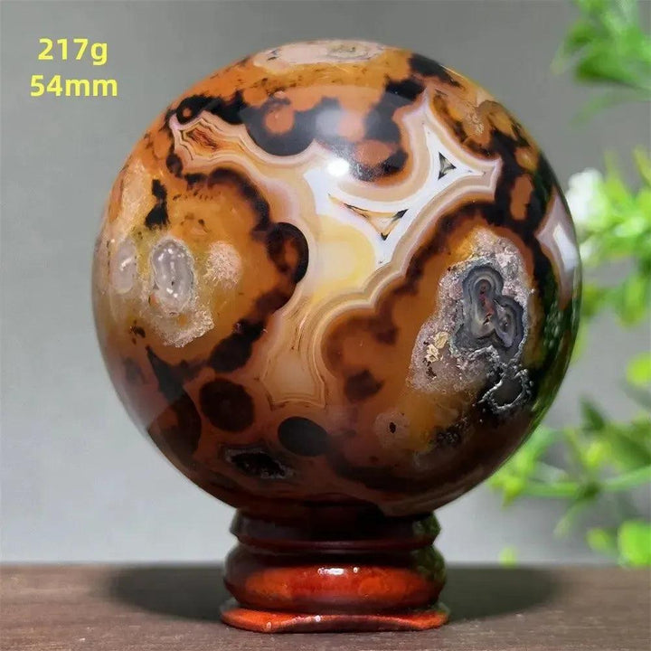 Polished Black Banded Agate sphere with dramatic black, charcoal, and white striations on a wooden stand.