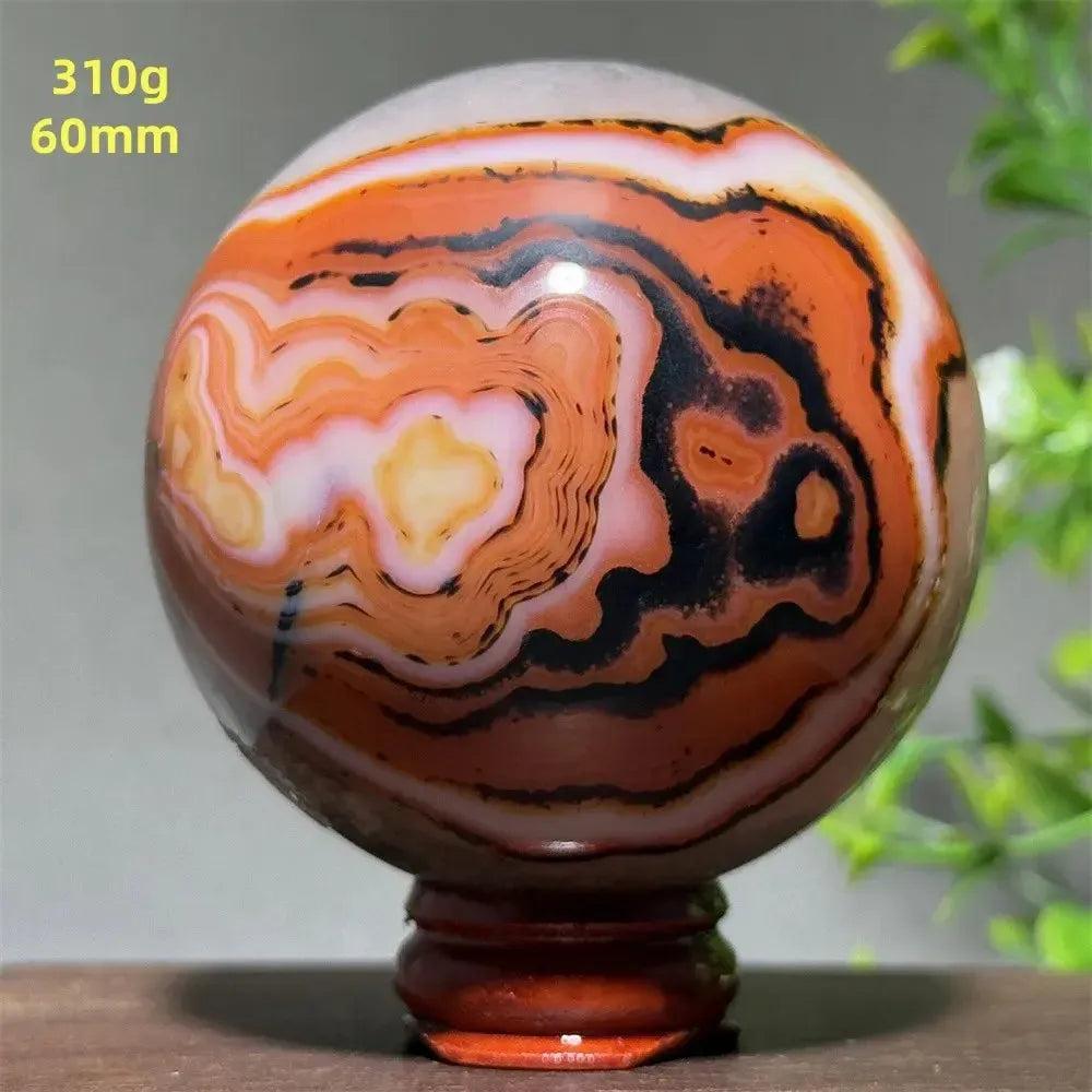 Polished Black Banded Agate sphere with dramatic black, charcoal, and white striations on a wooden stand.