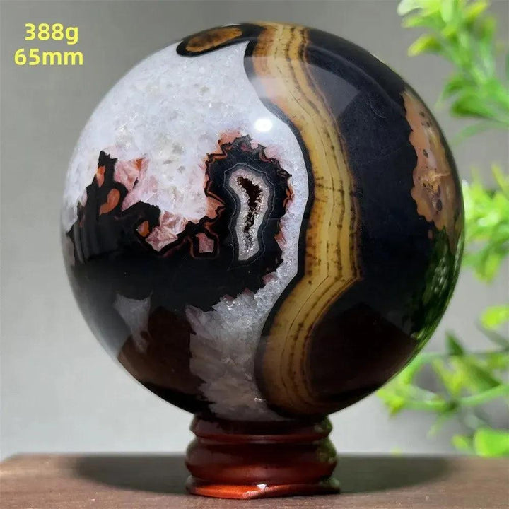 Polished Black Banded Agate Sphere with dramatic black, charcoal, white, and brown striations on a wooden stand.