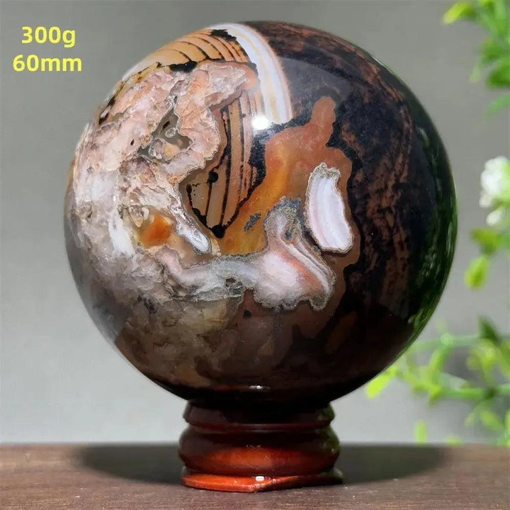 Polished Black Banded Agate sphere with dramatic black, charcoal, and white striations on a wooden stand.