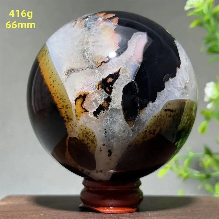 Black Banded Agate Sphere with striking black, charcoal, white, and orange striations on a wooden stand.
