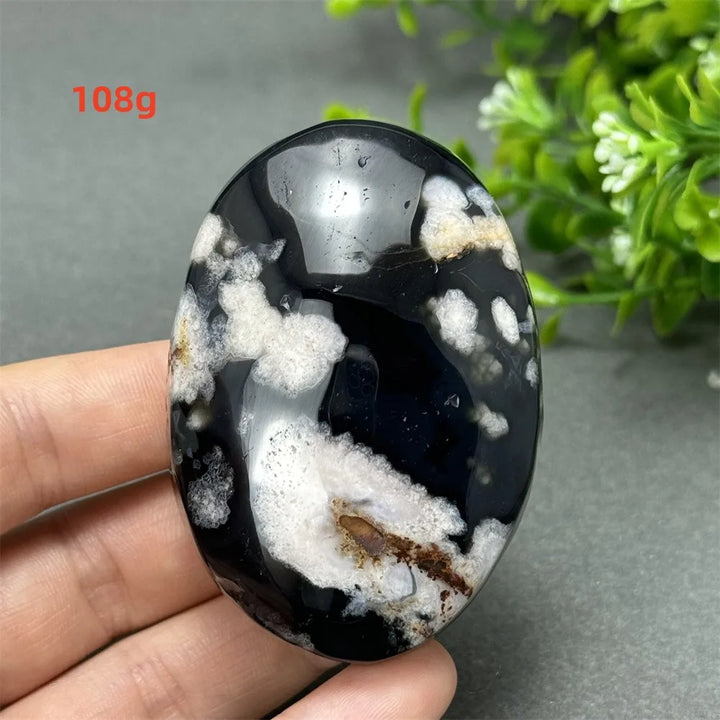 108g Black Cherry Blossom Agate palm stone with a deep charcoal base and cream floral dendrites for grounding energy.