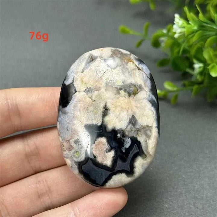 Black Cherry Blossom Agate palm stone with charcoal base and blush floral dendrites for Root Chakra grounding.