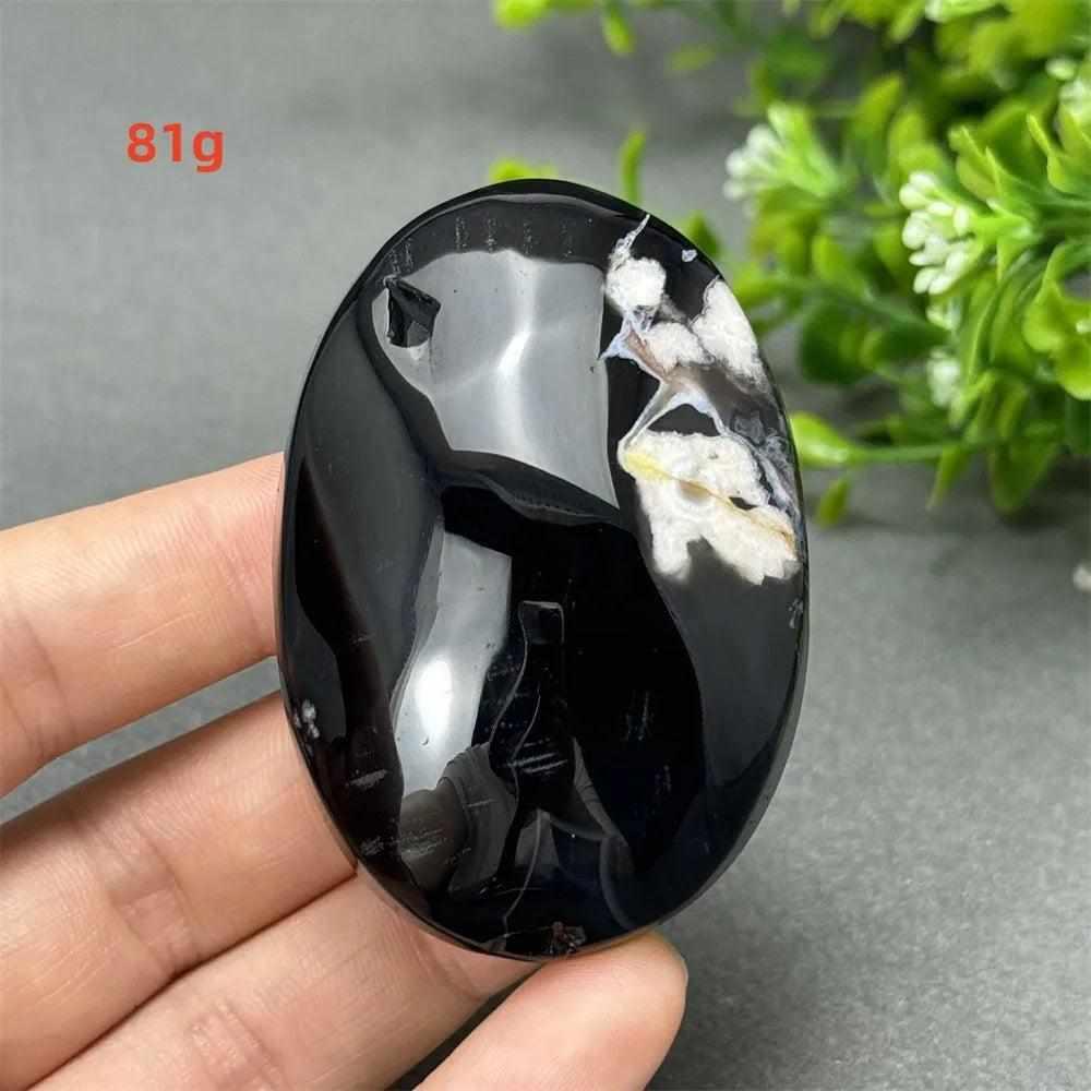 81g Black Cherry Blossom Agate palm stone with a deep charcoal base and elegant cream floral dendrite patterns.