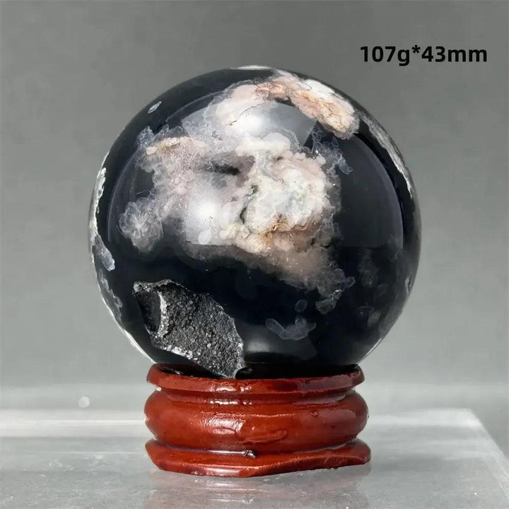 Stunning Black Cherry Blossom Agate Sphere with dramatic dark and light floral patterns on a wooden stand.