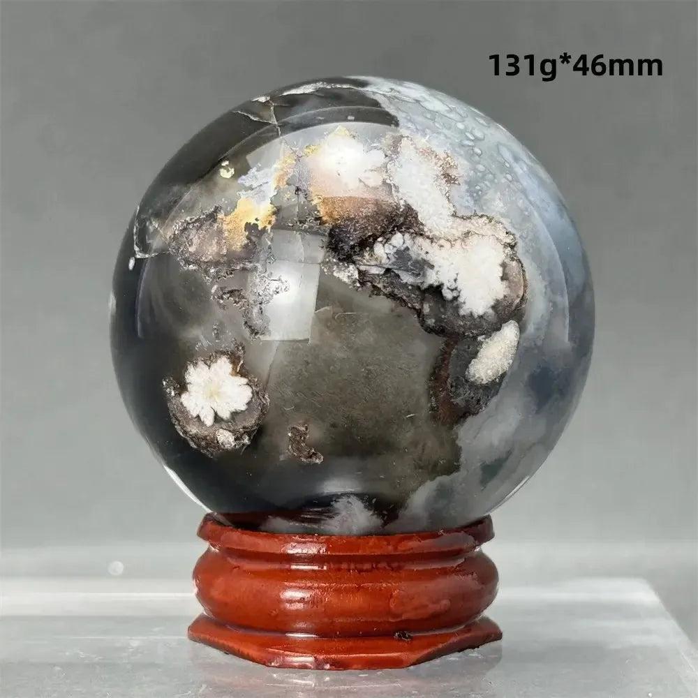 Black Cherry Blossom Agate Sphere, 46mm, with dramatic dark and light floral banding on a red wooden stand.