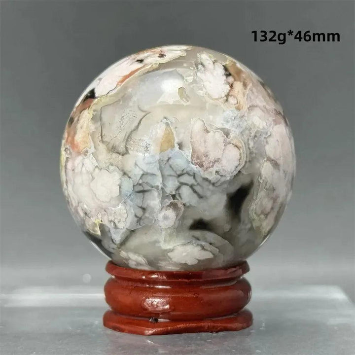 Black Cherry Blossom Agate Sphere, 46mm, featuring dramatic dark and light floral patterns on a wooden stand.