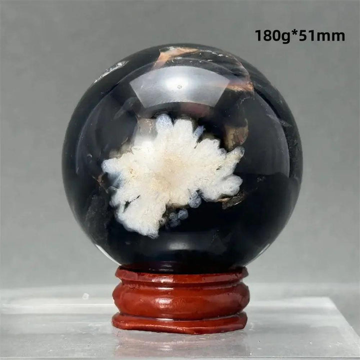 Black Cherry Blossom Agate Sphere, a striking dark and light floral patterned crystal on a wooden stand.