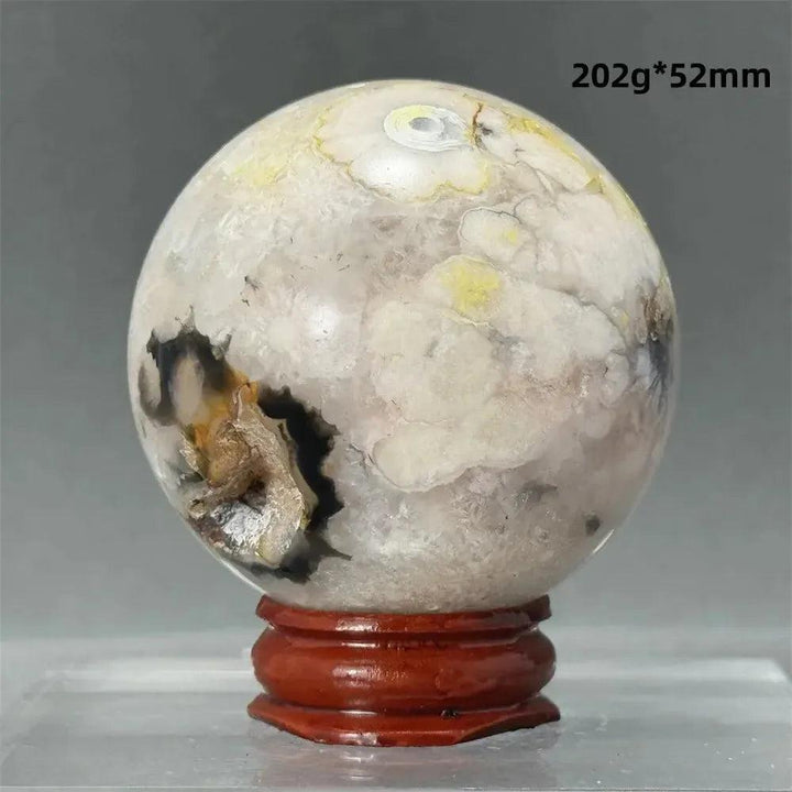Black Cherry Blossom Agate Sphere, 52mm, with dramatic dark and light floral banding on a wooden stand.