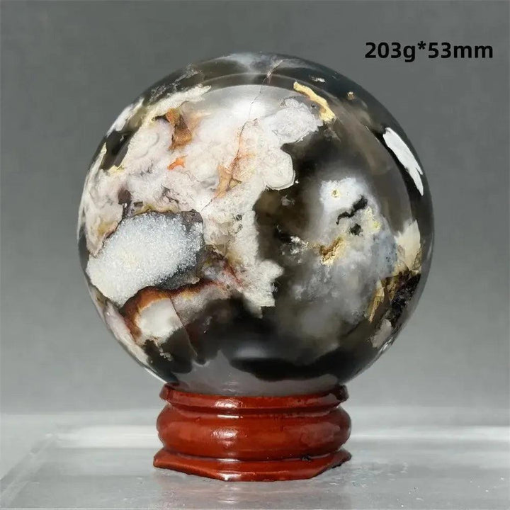Black Cherry Blossom Agate Sphere, a dramatic dark and light floral patterned chalcedony on a wooden stand.