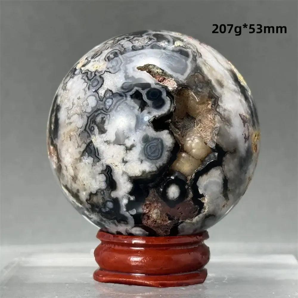 Black Cherry Blossom Agate Sphere with dramatic dark and light floral banding on a red wood stand.