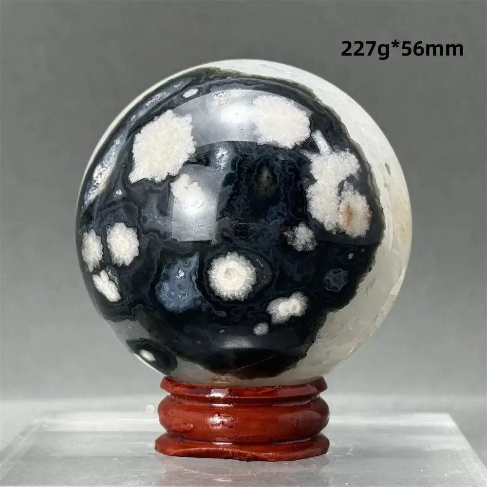 Black Cherry Blossom Agate Sphere with dramatic dark and light floral patterns on a wooden stand.