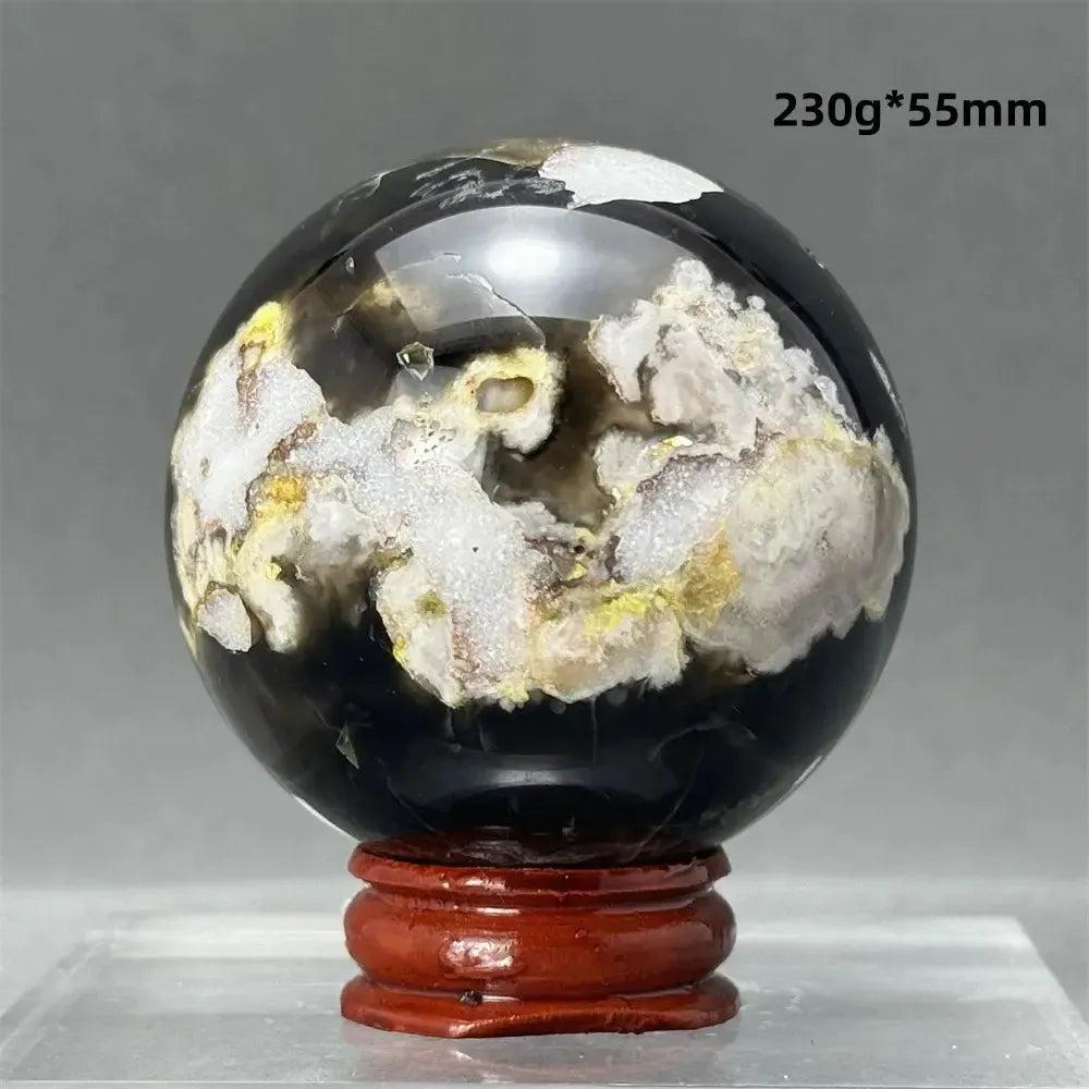 Black Cherry Blossom Agate Sphere with dramatic dark and light floral banding, on a wooden stand.