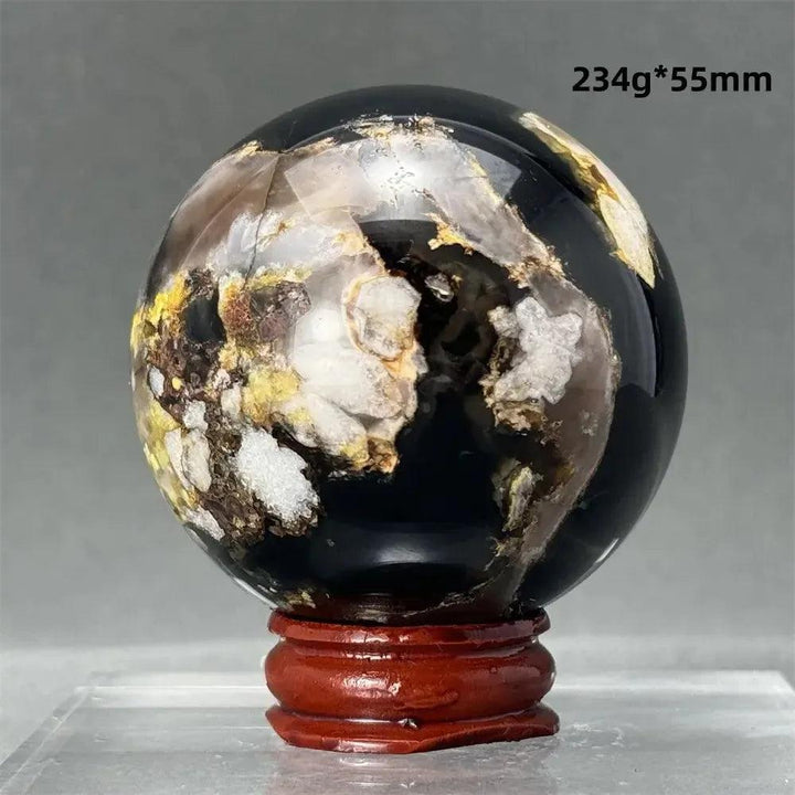 Black Cherry Blossom Agate Sphere with dramatic dark and light floral patterns on a wooden stand.