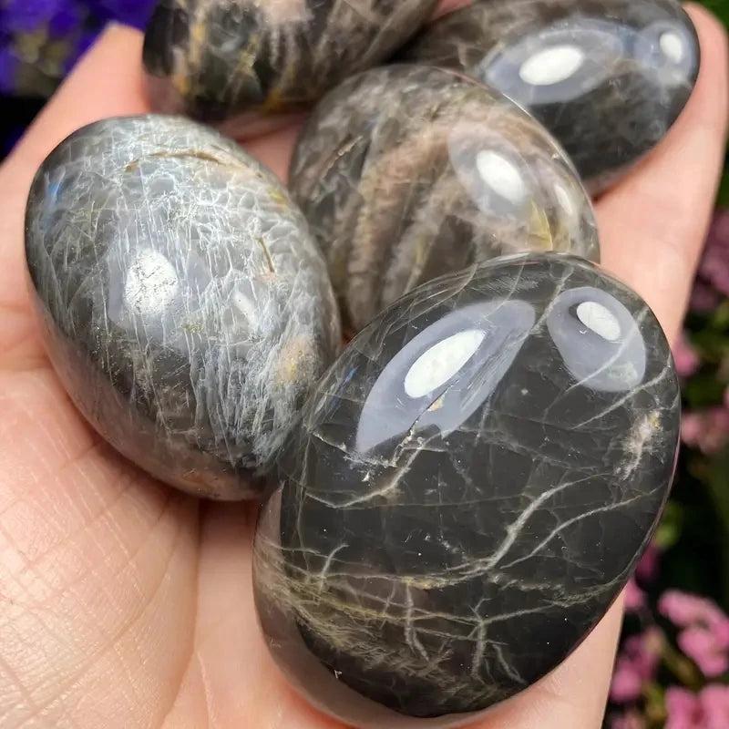 Polished black moonstone palm stone with natural veining, perfect for crystal healing, relaxation, and stress relief.