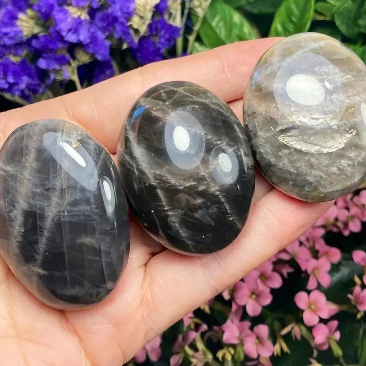 Polished black moonstone palm stones for relaxation, featuring smooth, natural dark crystal textures in a handheld size.