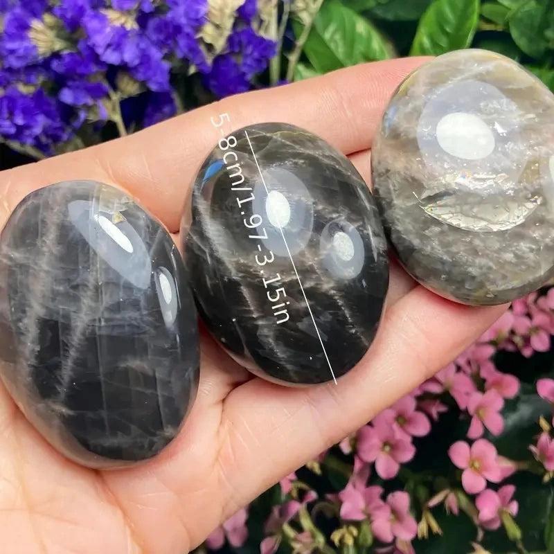 Polished black moonstone palm stones for relaxation, featuring smooth natural crystal textures in a 5-8cm handheld size.