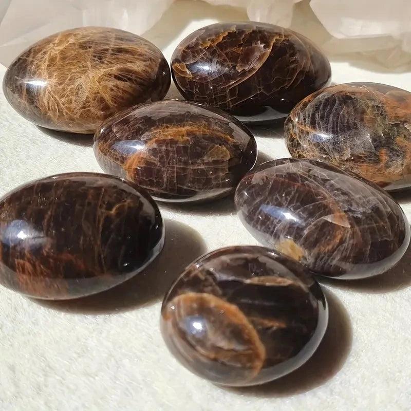 Polished black moonstone palm stones with rich brown veining, perfect for natural crystal healing and stress relief.