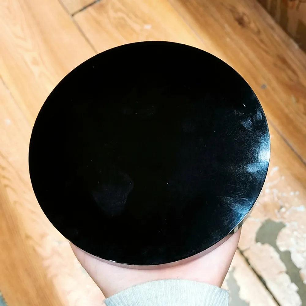 Polished black obsidian scrying mirror, round and deeply reflective, for divination and self-reflection.