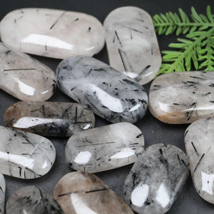 Polished Black Rutilated Quartz palm stones with unique needle-like inclusions for healing and home decor.