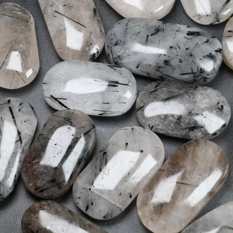 Polished natural Black Rutilated Quartz palm stones with unique black needle inclusions for healing and home decor.