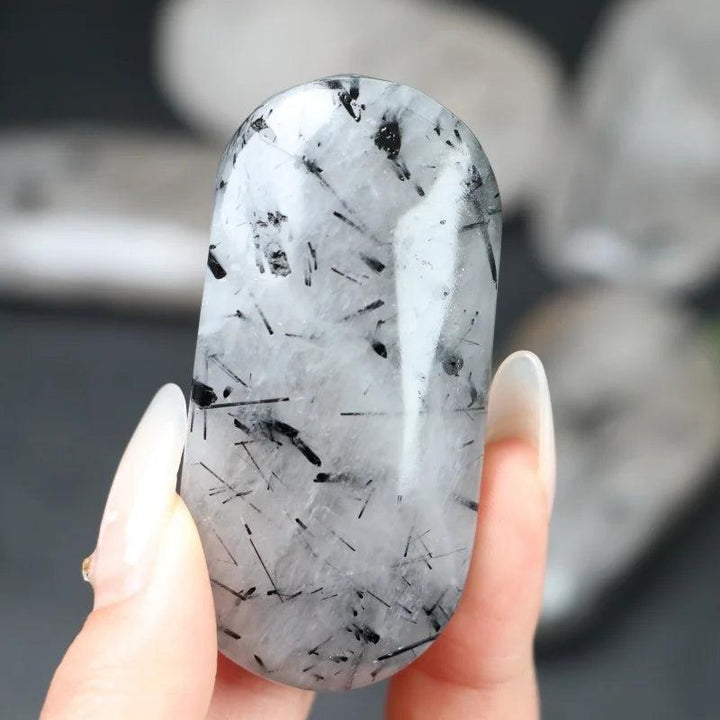 Polished Black Rutilated Quartz palm stone with striking needle-like inclusions for grounding and healing energy.