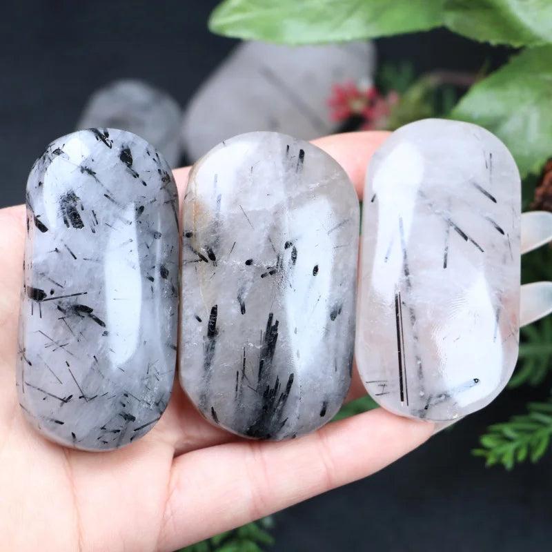 Three polished Black Rutilated Quartz palm stones with unique needle-like inclusions for healing and home decor.