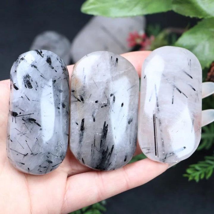Three polished Black Rutilated Quartz palm stones with unique needle-like inclusions for healing and home decor.