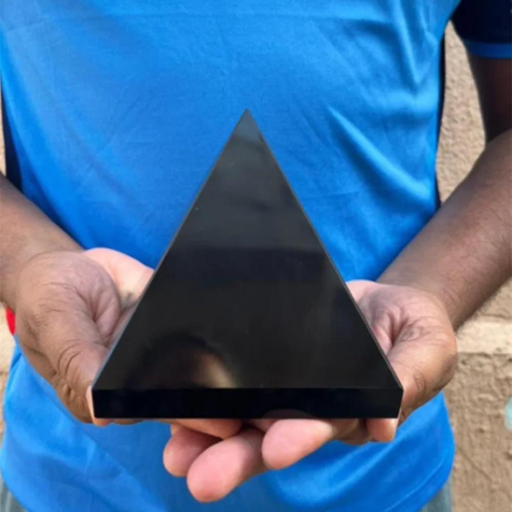 Hand-held Black Tourmaline Crystal Carved Protection Pyramid, showcasing its deep black color and polished finish.