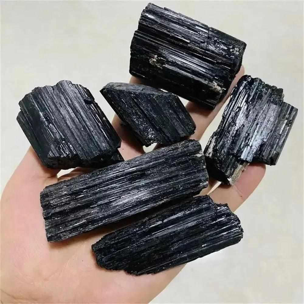 Handheld raw black tourmaline stones with natural striated texture, perfect for healing and home decor.