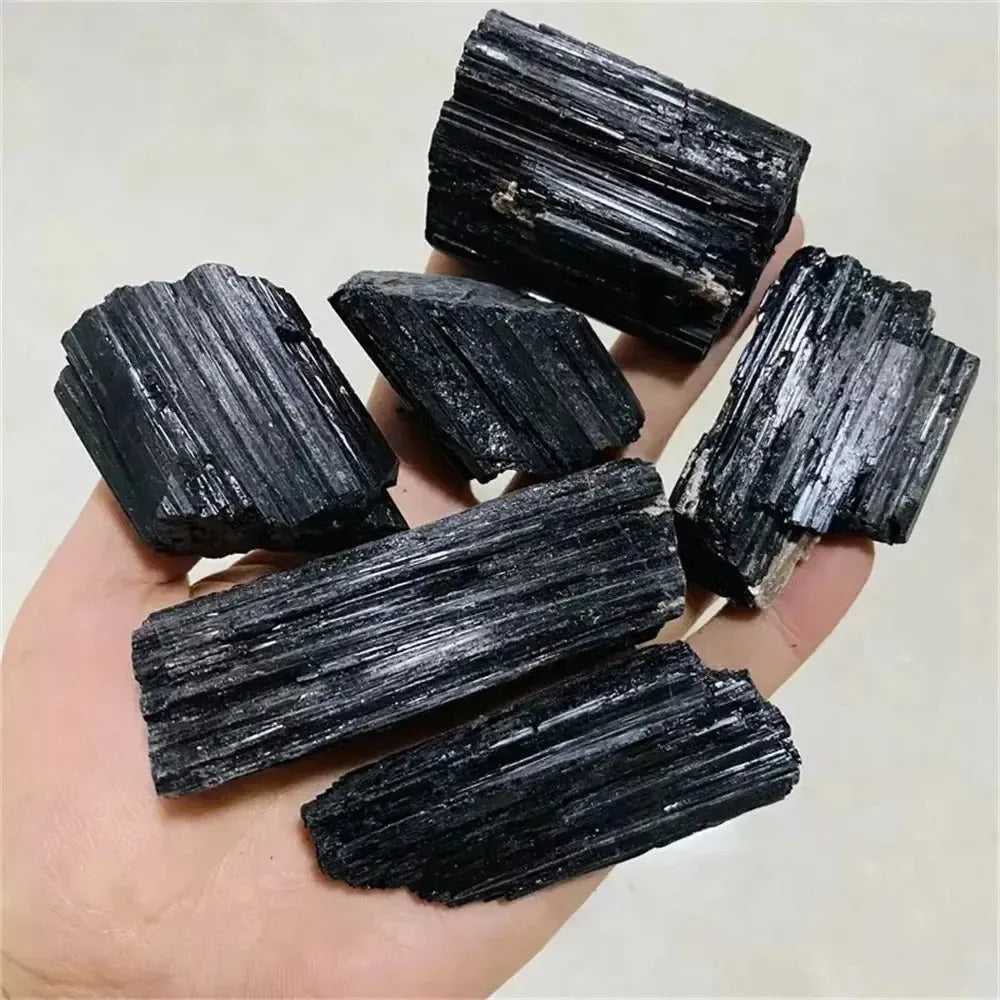 Handheld raw black tourmaline stones with natural striated texture, perfect for healing and home decor.